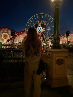 a woman standing in front of a carnival ride at night