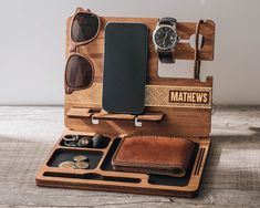 a wooden case with sunglasses, watch and other items in it sitting on top of a table