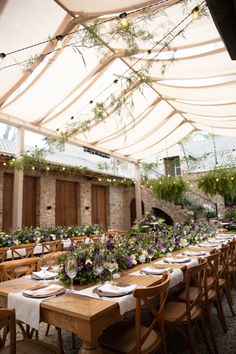 an outdoor dining area with tables and chairs under a canopy covered by lights, surrounded by greenery