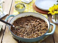 a pot filled with beans sitting on top of a table next to plates and flowers