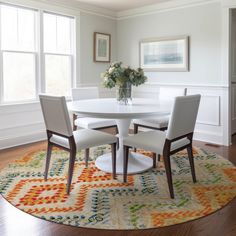 a dining room table with four chairs and a rug on the floor in front of it