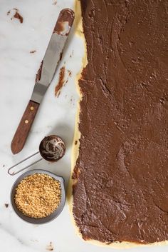 a chocolate cake sitting on top of a white counter next to a knife and measuring spoon