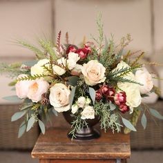 a vase filled with lots of flowers on top of a wooden table next to a couch