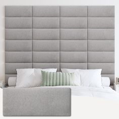 a bed with white pillows and gray headboard