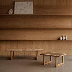 two wooden benches sitting next to each other in front of a shelf with vases on it