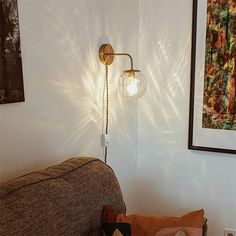 a lamp that is on the side of a wall next to a couch with pillows