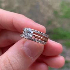 someone is holding their engagement ring in their hand with the wedding band on top of it