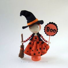 a doll with a witch hat holding a boo sign