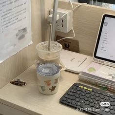 a desk with a laptop, keyboard and coffee cup on it next to a calculator