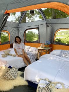 a woman sitting on top of two beds in a tent