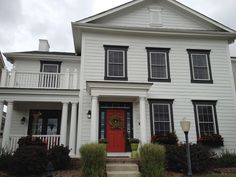 a white two story house with red front door