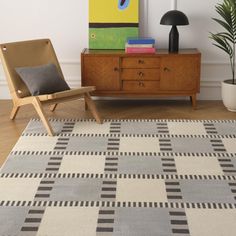 a living room area with a chair, rug and painting on the wall behind it