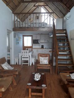 a living room filled with furniture next to a wooden stair case on top of a hard wood floor