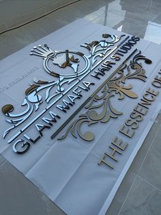 the entrance sign to the building is made out of metal and has gold lettering on it