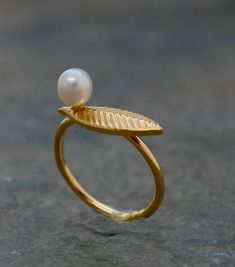 Gold Pearl Ring, Bridesmaid Gift, Gold Leaf Ring, Leaf Ring, Leaf jewelry, Bridal Accessories, Bridesmaid Jewelry, Unique Engagement RingDainty gold leaf ring with a white pearl is the perfect gift for bridal or bridesmaid to wear in your wedding day or every day. A beautiful engagement ring, features 22 karat gold plated brass, decorated with one beautiful leaf, and freshwater pearl. The ring circles the finger to give you that fairy look.Perfect for fairies and other forest creatures. Dimensio Gold Dainty Pearl Ring For Wedding, Minimalist Pearl Drop Ring For Wedding, Dainty Open Pearl Ring For Wedding, Minimalist Wedding Pearl Ring With Pearl Drop, Delicate Pearl Open Ring For Weddings, Gold Open Ring Pearl Ring For Wedding, Minimalist Gold Pearl Ring For Wedding, Gold Open Pearl Ring For Wedding, Gold Wedding Rings With Pearl Drop