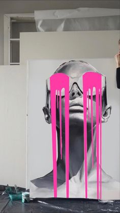 a woman standing in front of a painting with pink dripping paint on it's face