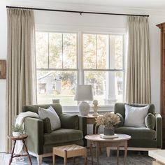 a living room with two green chairs and a coffee table in front of a large window