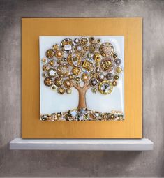 a white and gold wall hanging with a tree made out of buttons on top of it