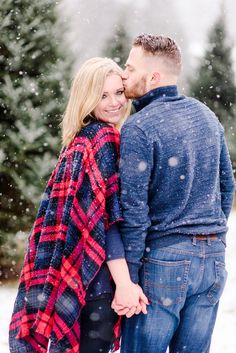 a man and woman are standing in the snow with their arms wrapped around each other