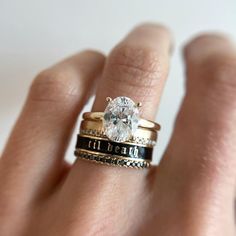 a woman's hand holding a ring with a diamond in the middle and two bands around it