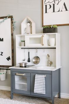 a gray and white play kitchen in a child's room with shelves above the sink