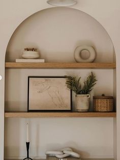 an arch in the wall above a shelf with vases and other items on it