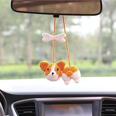 two stuffed animals hanging from the dashboard of a car