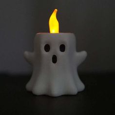 a white candle that is lit up with a ghost face on it's side