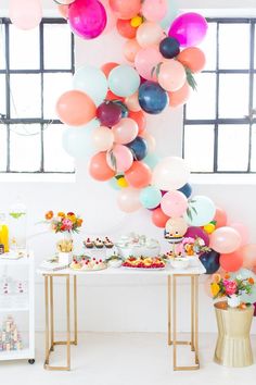 a table topped with lots of balloons and desserts