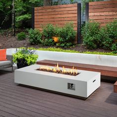 a fire pit sitting on top of a wooden deck next to a bench and trees