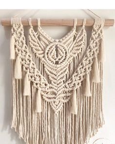 a macrame wall hanging with tassels and beads on a wooden hanger