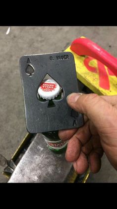 a hand holding a bottle opener with some stickers on it