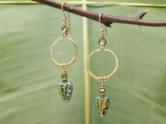 "Elegant Heart-shaped iridescent leaf drop hoop earrings. Handcrafted, hammered, & wire wrapped in gold. One of a kind design. ► MATERIALS: . Golden brass hoop earrings. 14 K gold fill ear wires. Swarovski crystals, Czech art glass, 14 K fill gold beads   ► SIZE: Small 3/4 inch round with 3/4\" leaf drop dangle ► Custom orders upon request: lever-back clasps, posts, etc. ►Perfect for gift giving  Gift boxed with mini postcard/gift card included ► For more visit: Analeihawaii.etsy.com ► Custom or Unique Wire Drop Earrings, Unique Gold Heart Earrings, Unique Wire Dangle Jewelry, Dangle Wire Hoop Earrings For Gift, Dangle Wire Hoop Earrings As A Gift, Dangle Hoop Earrings As Gift, Gift Dangle Hoop Earrings, Heart Shaped Leaf, Earrings Gold Hoop