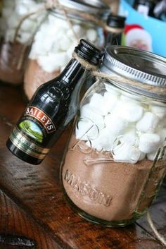 two mason jars filled with marshmallows sitting on top of a wooden table