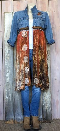 a woman standing next to a wooden wall wearing a jean jacket with flowers on it