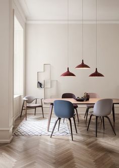 a dining table with four chairs and three pendant lights hanging from it's ceiling