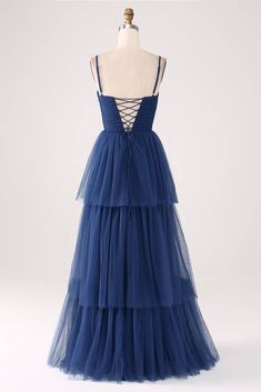 a dress on a mannequin with straps and blue tulle, in front of a white background