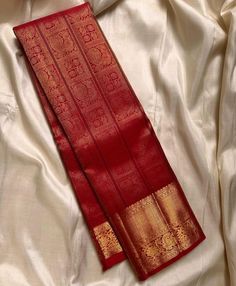 two red and gold sari laying on top of a white sheet