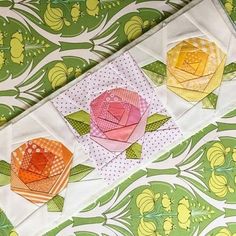 three paper flowers are sitting on top of a green and white tablecloth with polka dots