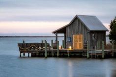 a small wooden house sitting on top of a pier next to the ocean at dusk