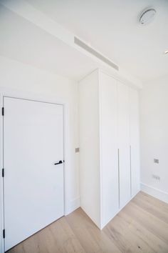 an empty room with white walls and wooden flooring is seen in this image, there are two doors on either side of the wall