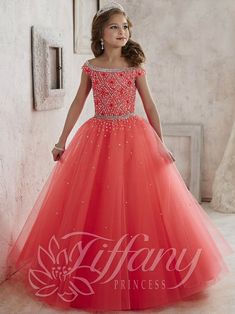 Your sweet girl will make a grand entrance in this beaded long off the shoulder dress with A-line skirt by Tiffany Princess 13458. Pageant-style off-the-shoulder gown with intricate beaded pattern on the bodice and waistband and scattered sequins over the full tulle ball gown skirt. Lace-up back. House of Wu Tiffany Princess Collection Spring 2016 Style Number: 13458 Fabric: Tulle Silhouette: A-line Neckline: Scoop Sleeve: Off the Shoulder, Cap Sleeves Colors: Hot Coral, Turquoise, White Sizes: Junior Pageant Dresses, Military Ball Dresses, Kids Frocks Design, Girls Pageant Dresses, Kids Gown, Tulle Ball Gown, Kids Frocks, Pageant Gowns, Gowns For Girls