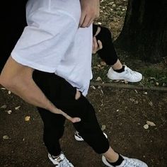 a woman in white shirt and black leggings holding onto another person's arm