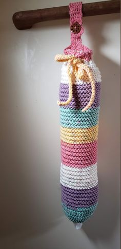 a colorful crocheted bag hanging from a hook on a white wall with a wooden handle