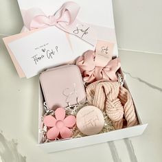 an open box with pink and white items in it on a marble counter top next to a card