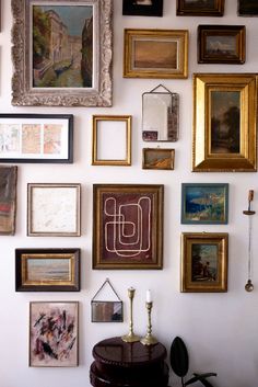 a wall with many framed pictures on it