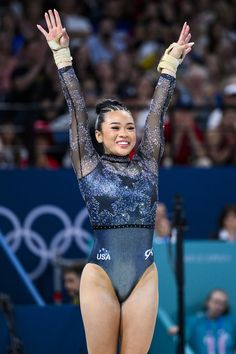 a woman in a blue leotard is holding her hands up and smiling at the camera