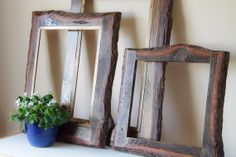 two wooden frames sitting on top of a white shelf next to a potted plant