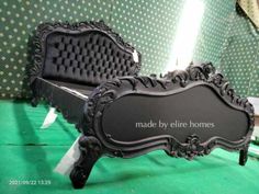 an ornate black bed frame sitting on top of a green floor