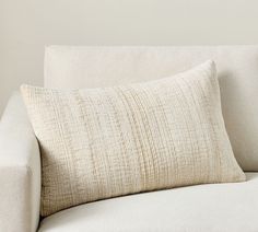 a white couch with a pillow on it's back and the rest of its arm